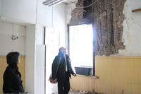 Tsooru rahvamaja juhataja Kalle Nurk näitab Antsla volikogu liikmetele kohta Lepistu koolimaja seinas, kus palgid on räästa all niiskuse mõjul läbi mädanenud. Foto: Võrumaa Teataja