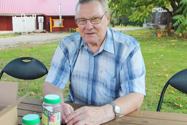 Taarapõllu talu peremees Edgar Kolts tutvustab tänavuse aasta tegemisi, tema ees laual on kunstniku kujundatud suur marjakrõpsupurk, selja taga on näha kuulsat marjakrõpsude tootmise maja.     Foto: INNO TÄHISMAA