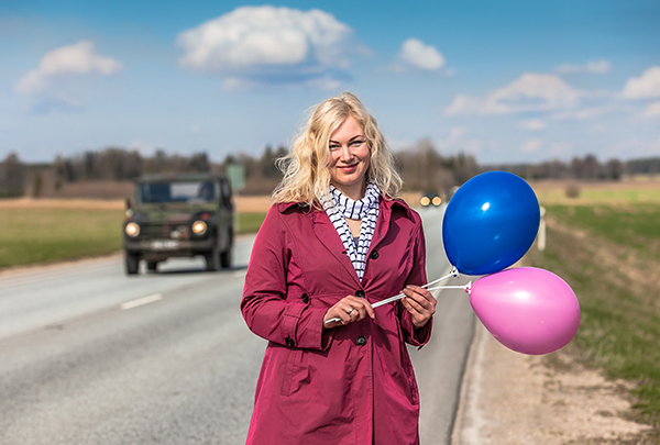 Britt Vahter eile Võrumaa info- ja tervitusvärava plaanitavas asukohas Tartu maanteel. Taustal möödumas tänavusele Kevadtormile saabuvad kaitseväe sõidukid.  Foto: FOTOSFERA / ANDREI JAVNAšAN