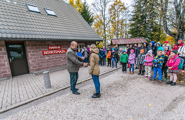 Haanja vallavanem Juri Gotmans annab noortemaja ees võtmed üle Miina-Aleksandra Pihole. Suursündmust oli tunnistama tulnud terve Haanja koolipere – ligemale 60 õpilast. Foto: FOTOSFERA / ANDREI JAVNAŠAN