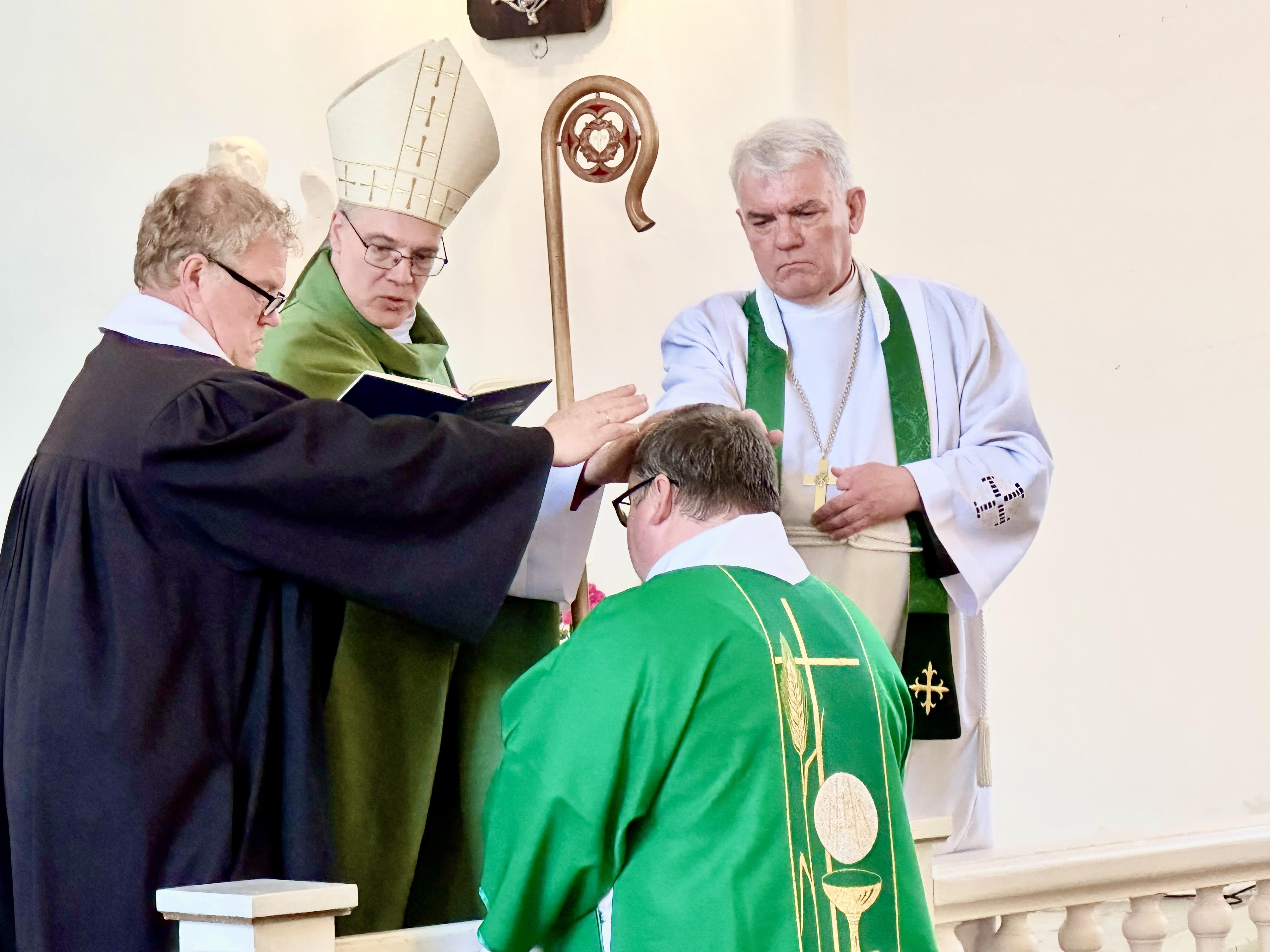 Ametisseseadmine. Võru praost Üllar Salumets (vasakult), Lõuna-Eesti piiskopkonna piiskop Marko Tiitus, Pärnu praost Tõnu Taremaa. Põlvitab diakon Jaanus Torrim. FOTO: Kalev Annom