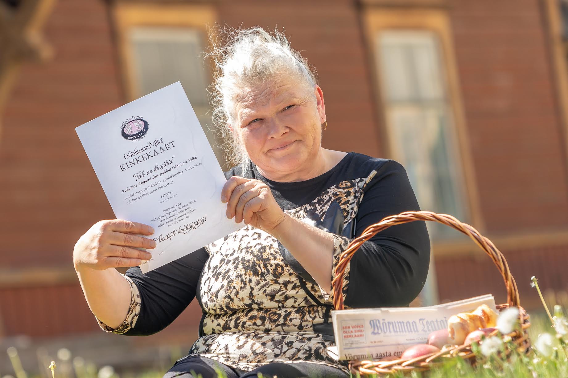 Seekordne auhinnavõitja Anita Pilt koos Ööbikuoru Villa kinkekaardiga oma kodu tagahoovis. Korvis on ise tehtud viineripirukad ning õunad. Anita Pilt on elanud kogu elu Võrus, armastab seda paika ega ihka kuskile mujale. Foto: AIGAR NAGEL