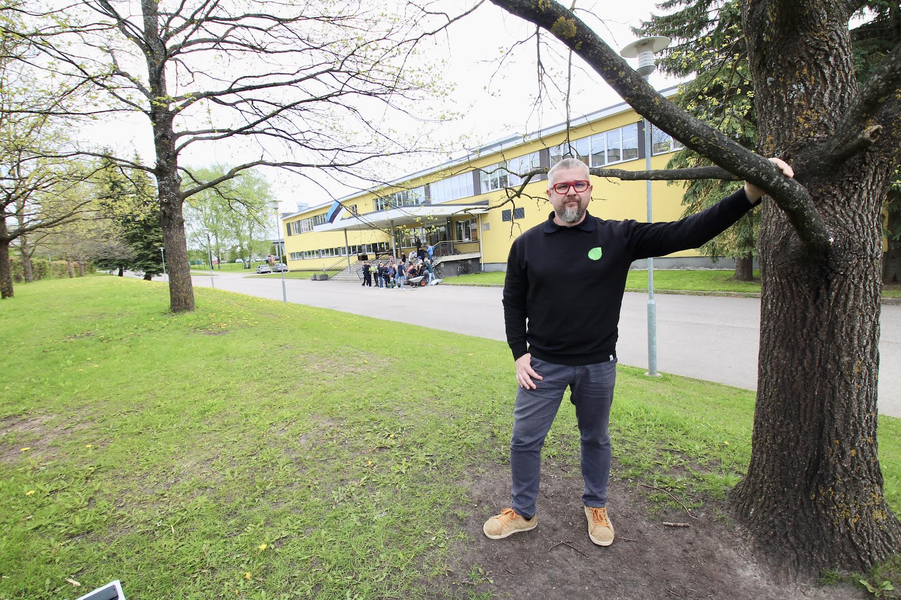 Tammede rea all seisev koolijuht Taavi Karu on selles koolimajas ise õppinud aastatel 1992–1995. Tänavu augustis saab täis viis aastat koolijuhina. Taamal istutavad õpetaja Merit Kundi 5.c õpilased loodusõpetuse õuesõppetunnis koolimaja ette lilli. Foto: KALEV ANNOM