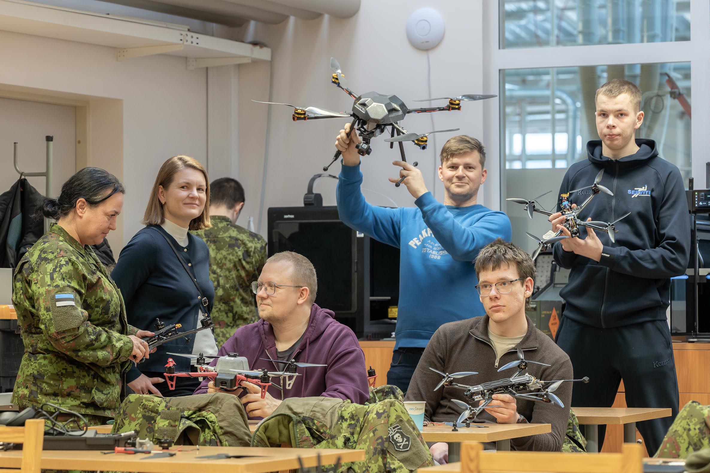 Vasakult: 2. jalaväebrigaadi teabeohvitser Jaanika Ojakõiv, Võrumaa haridus- ja tehnoloogiakeskuse direktor Eveli Kuklane, David Tiks, Toomas Tammiste, Indrek Martin Kuusik ja Andero Hääl väljaõppe eelviimasel päeval. Taustaks kogu väljaõppe jooksul kasuks olnud 3D-printerid. Foto: AIGAR NAGEL